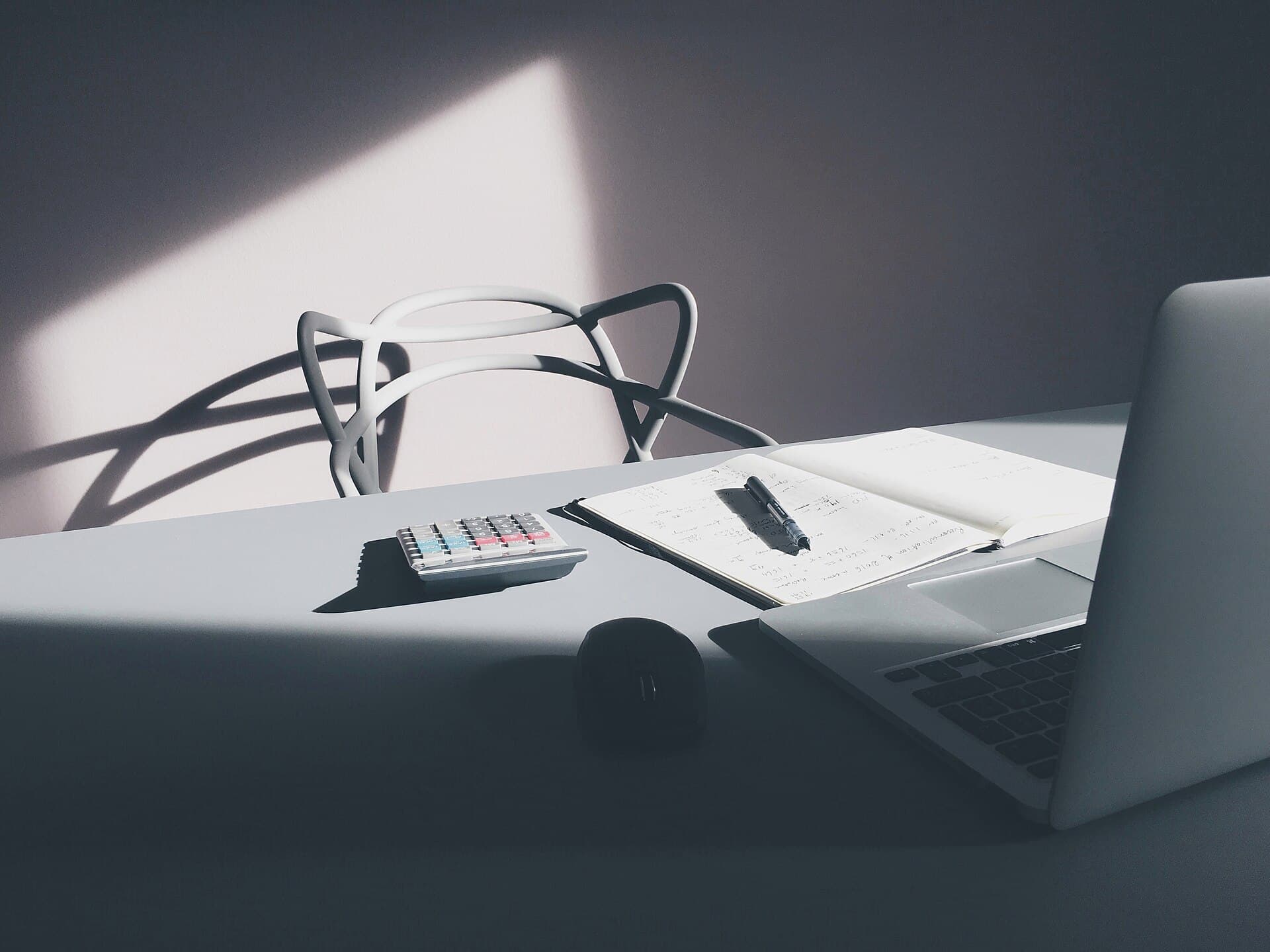 Laptop and calculator on a desk with a coffee cup