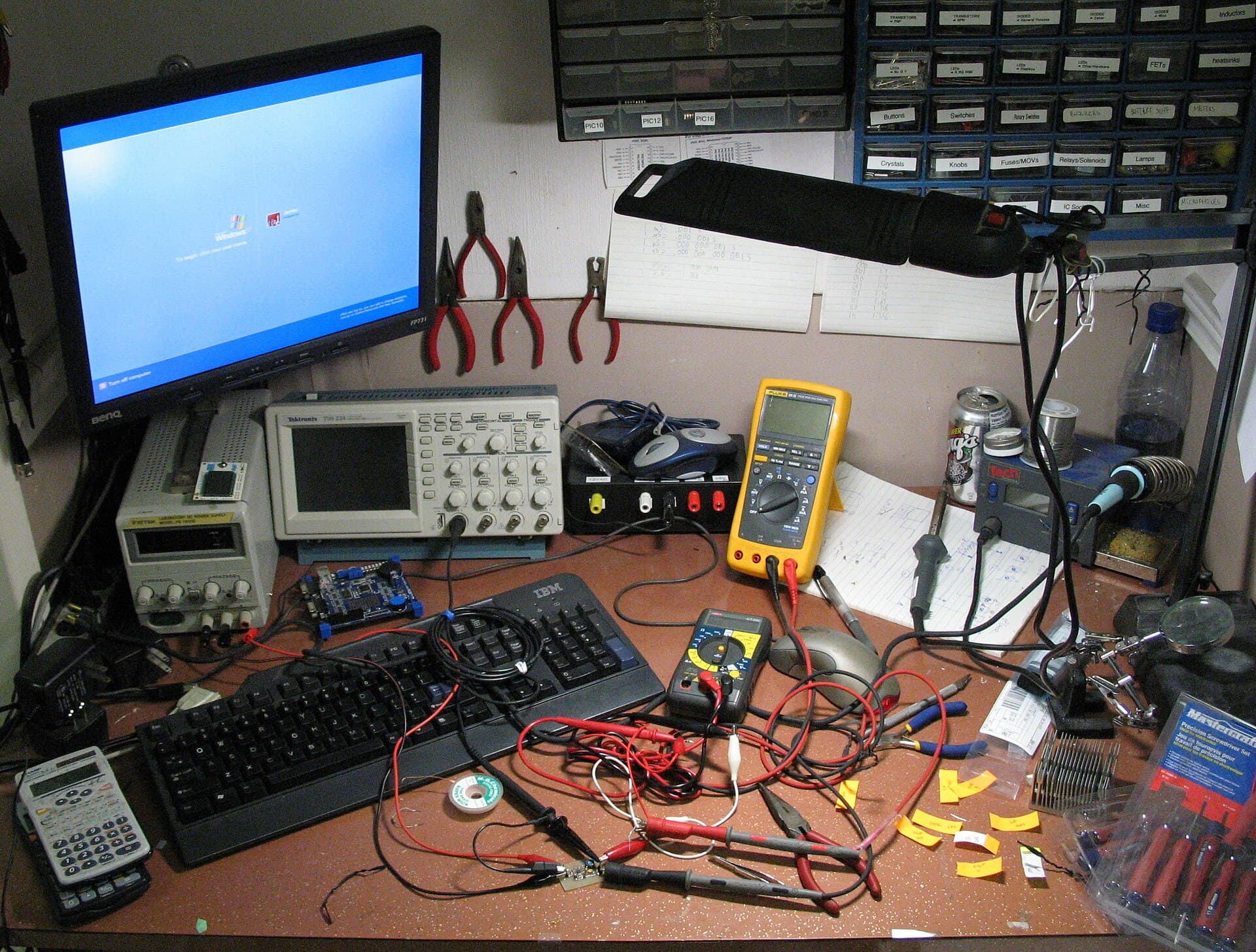 Electronics workbench with tools, parts and a vice
